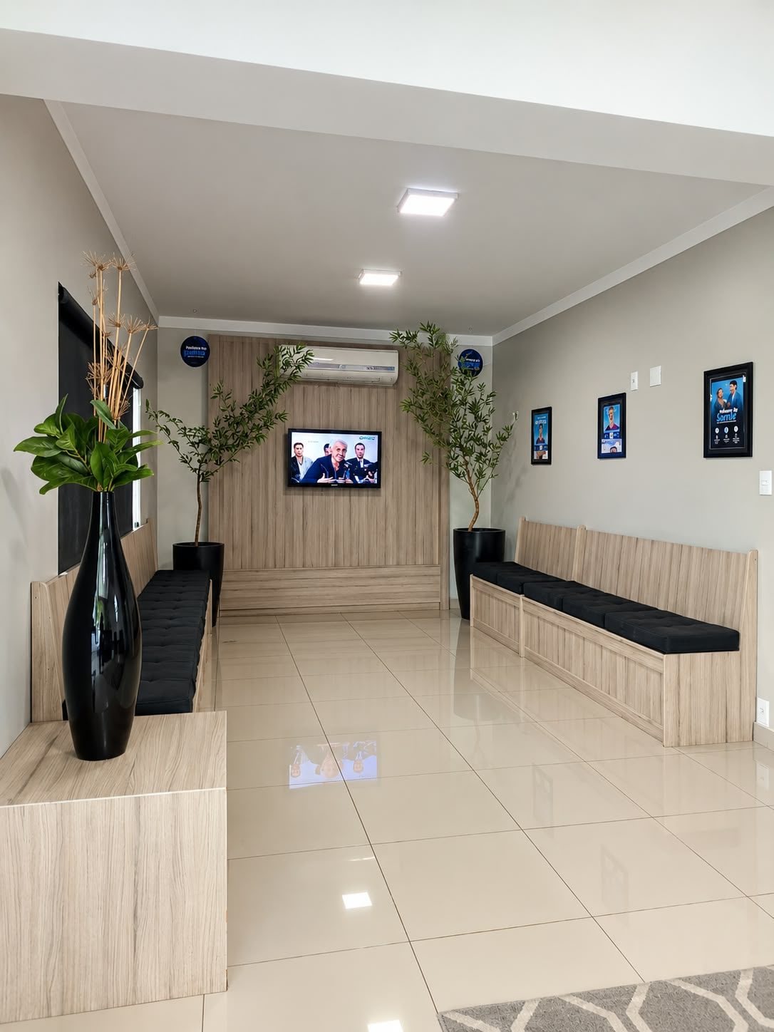 Sala de espera da Odontoclinic Sumaré, com bancos, televisão e plantas